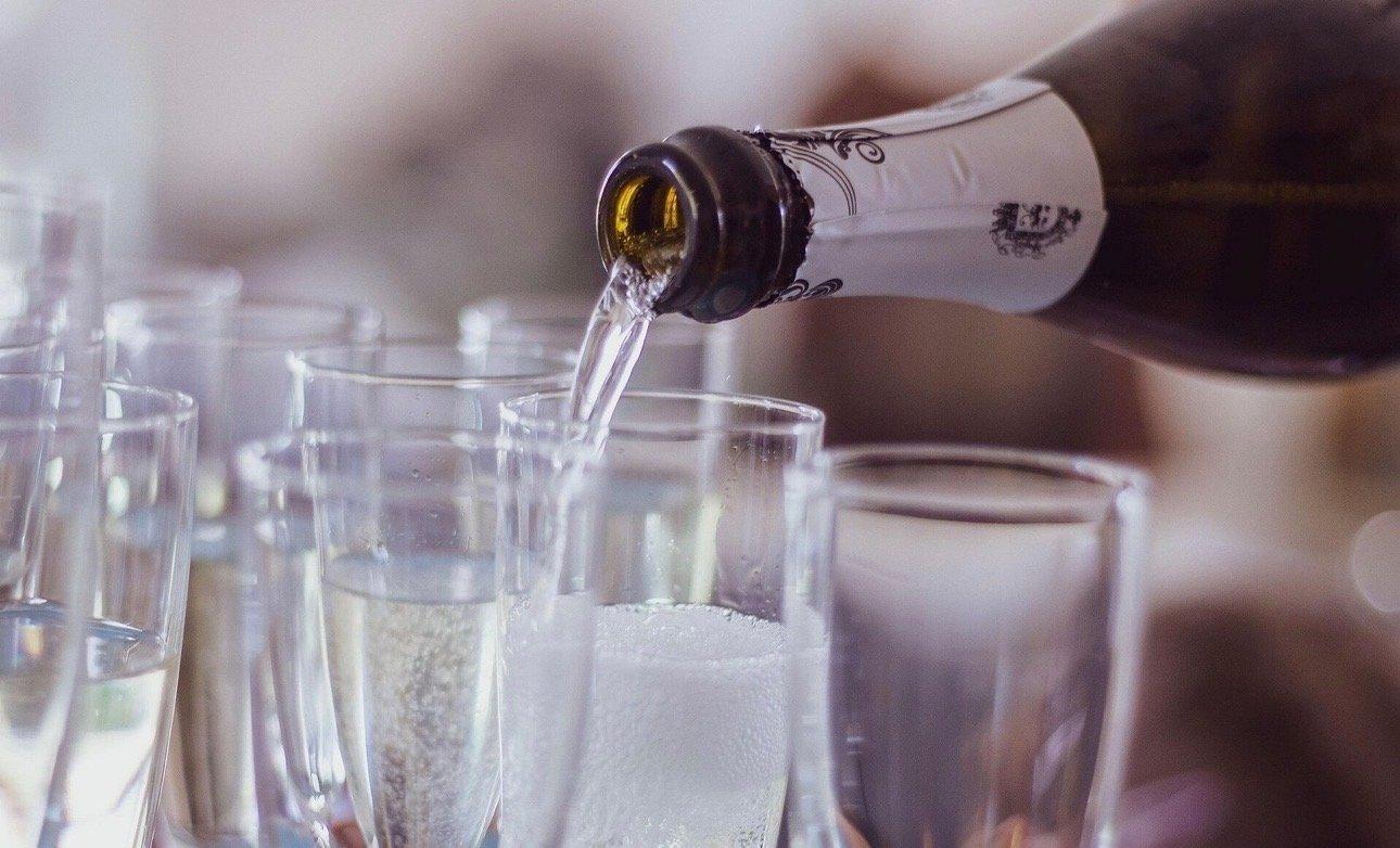Close-up of Prosecco being poured into glasses on board